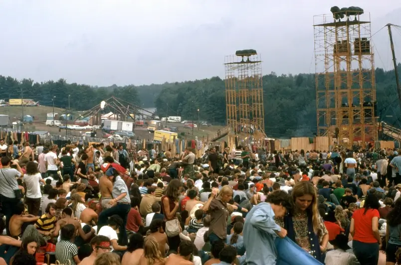 Uma foto de uma multidão de pessoas reunidas em um campo durante o festival de Woodstock em 1969