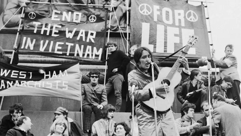 Jovens nos anos 60 em um protesto com um violão cantando rock como crítica social